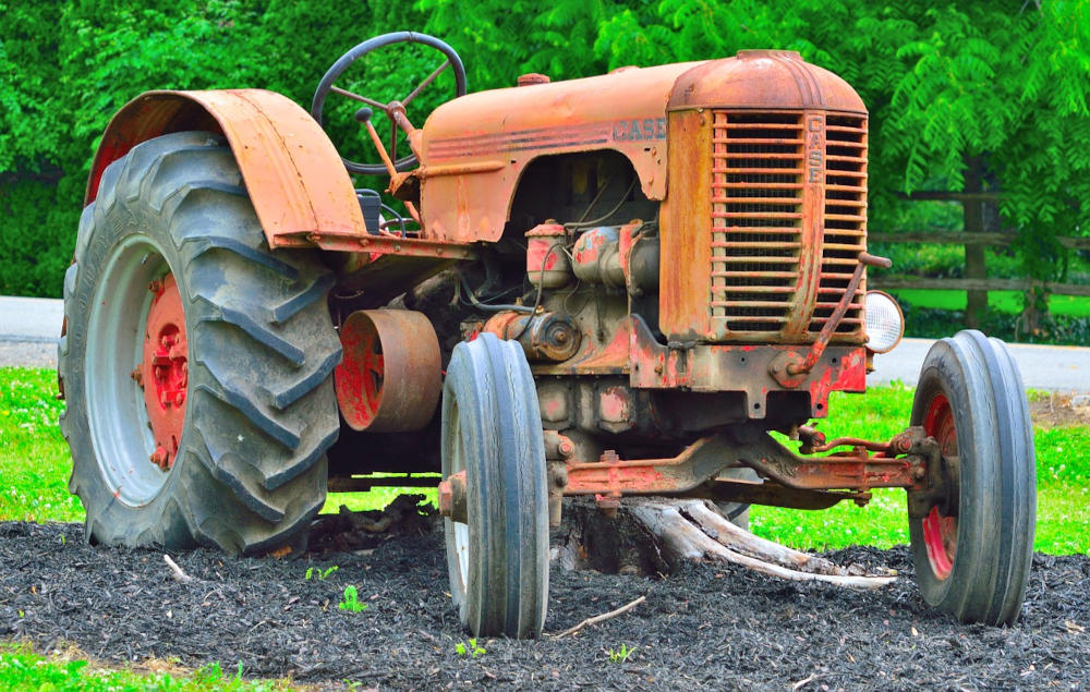An antique tractor painted orange with the biggest rear wheels